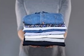 Attendant holding folded wash and fold laundry